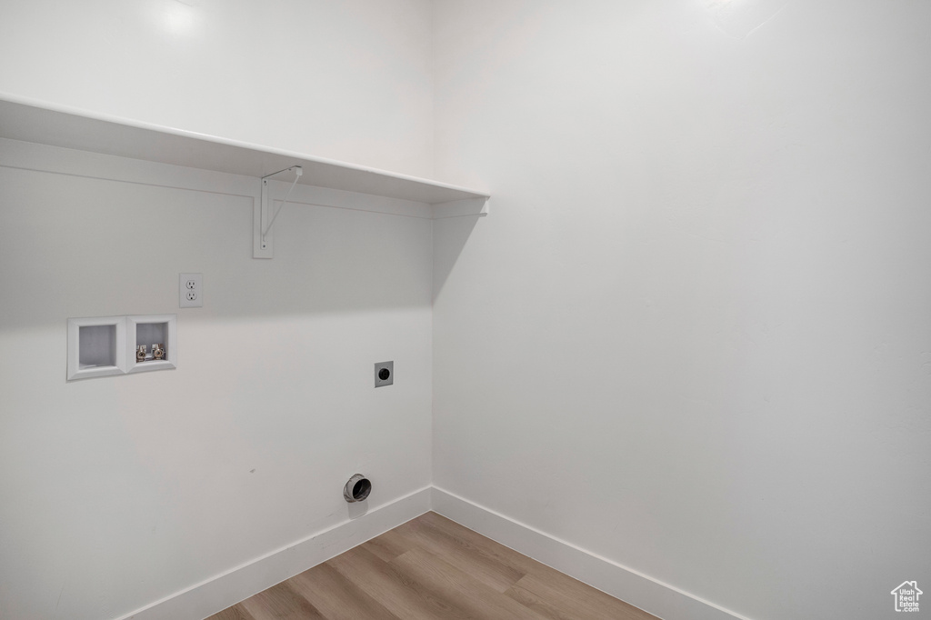 Laundry room with hookup for an electric dryer, hookup for a washing machine, light wood finished floors, and baseboards