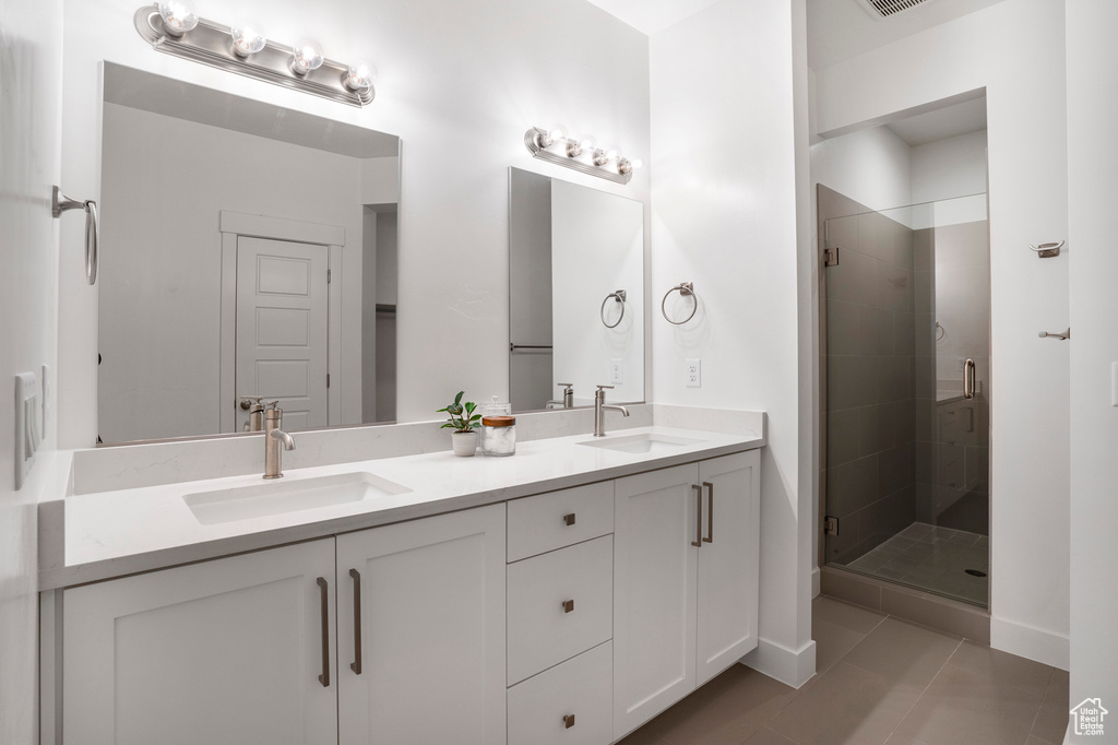 Bathroom with a shower stall, tile patterned flooring, double vanity, and baseboards