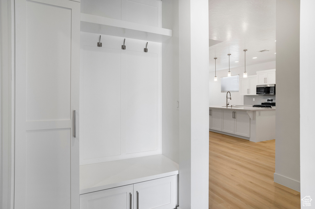 Mudroom with light wood finished floors, a sink, baseboards, and recessed lighting