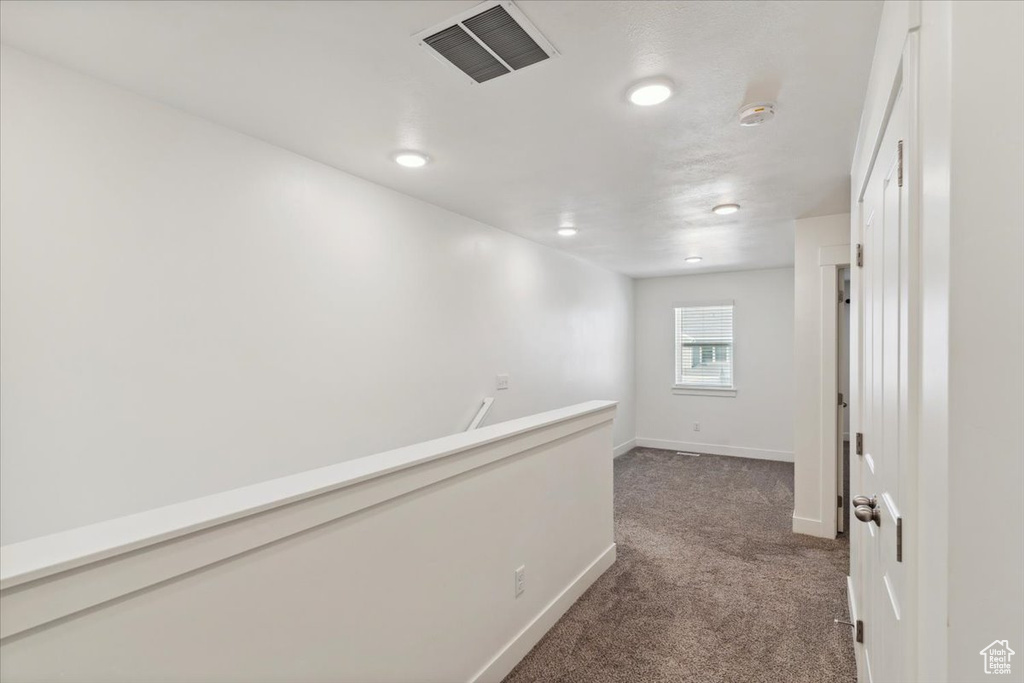 Hallway with dark carpet and baseboards