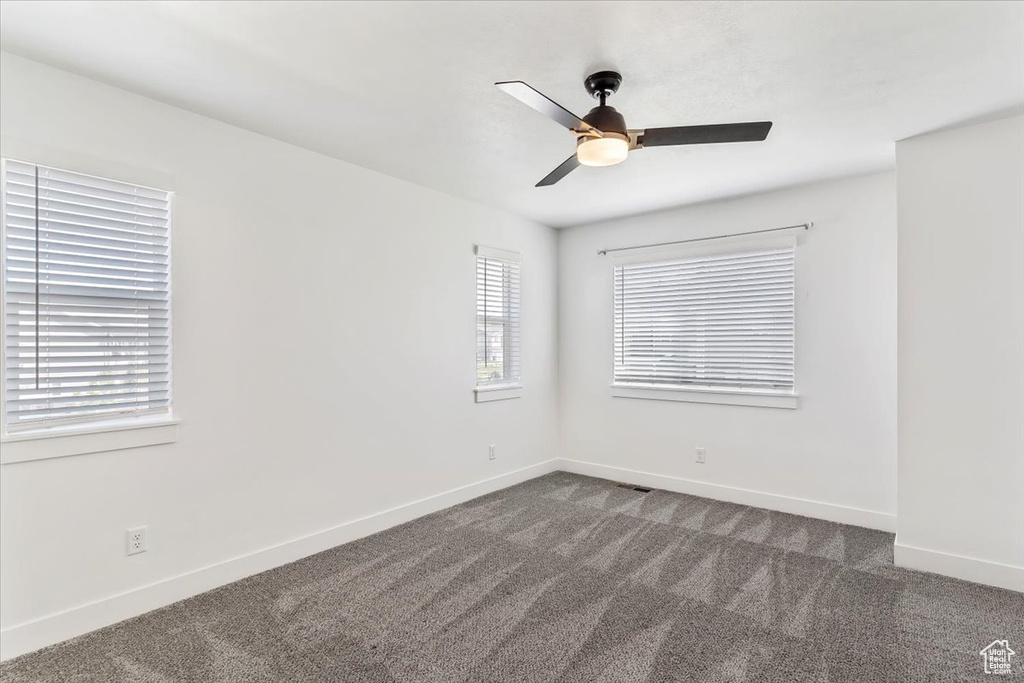 Empty room featuring carpet floors, healthy amount of natural light, baseboards, and a ceiling fan