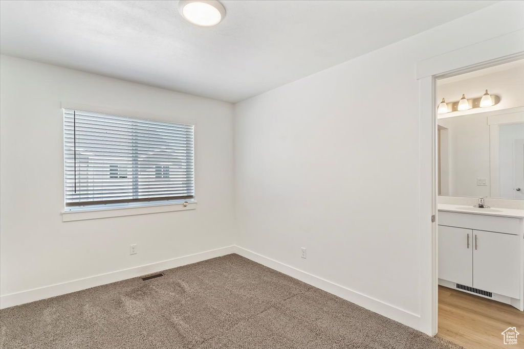 Spare room with a sink, baseboards, and light carpet