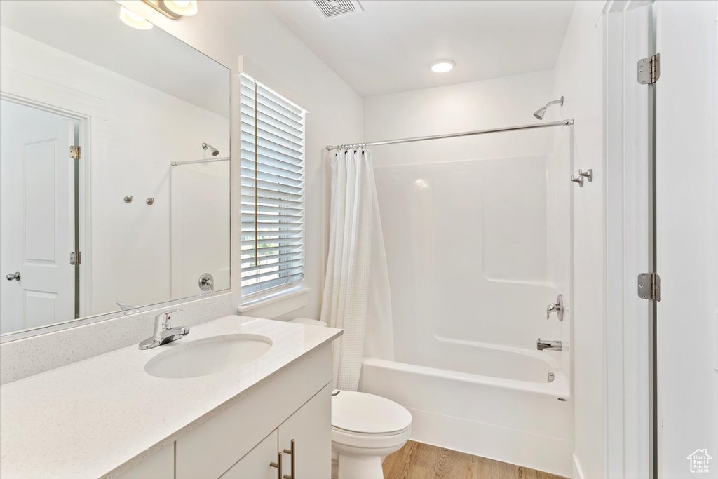 Full bathroom featuring shower / tub combo, vanity, toilet, and wood finished floors