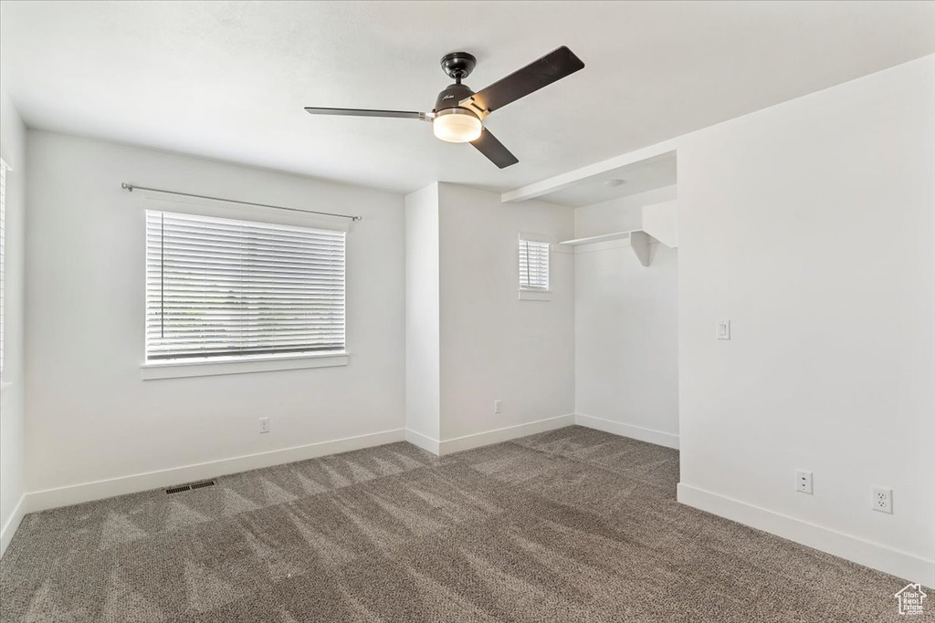Spare room featuring carpet floors, a ceiling fan, and baseboards