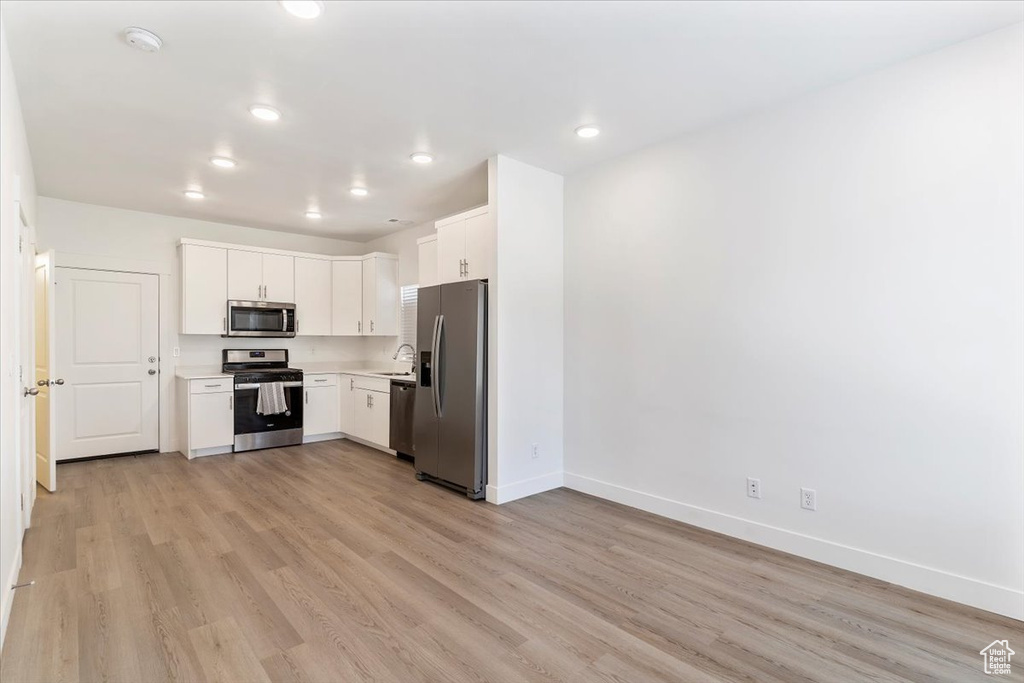 Kitchen featuring appliances with stainless steel finishes, baseboards, light countertops, light wood-type flooring, and recessed lighting
