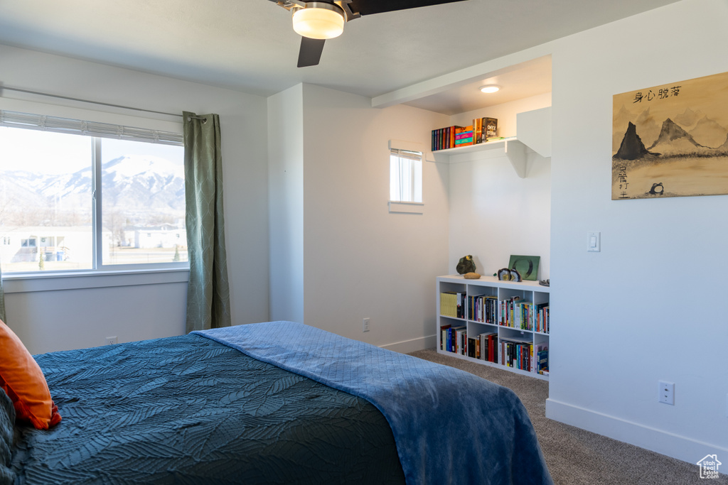 Bedroom with carpet, baseboards, a ceiling fan, and a mountain view