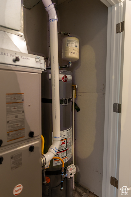 Utility room featuring strapped water heater