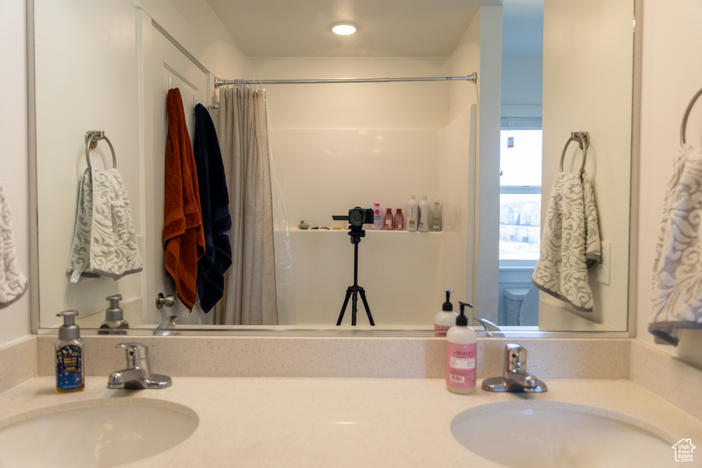 Bathroom featuring a shower with curtain and double vanity