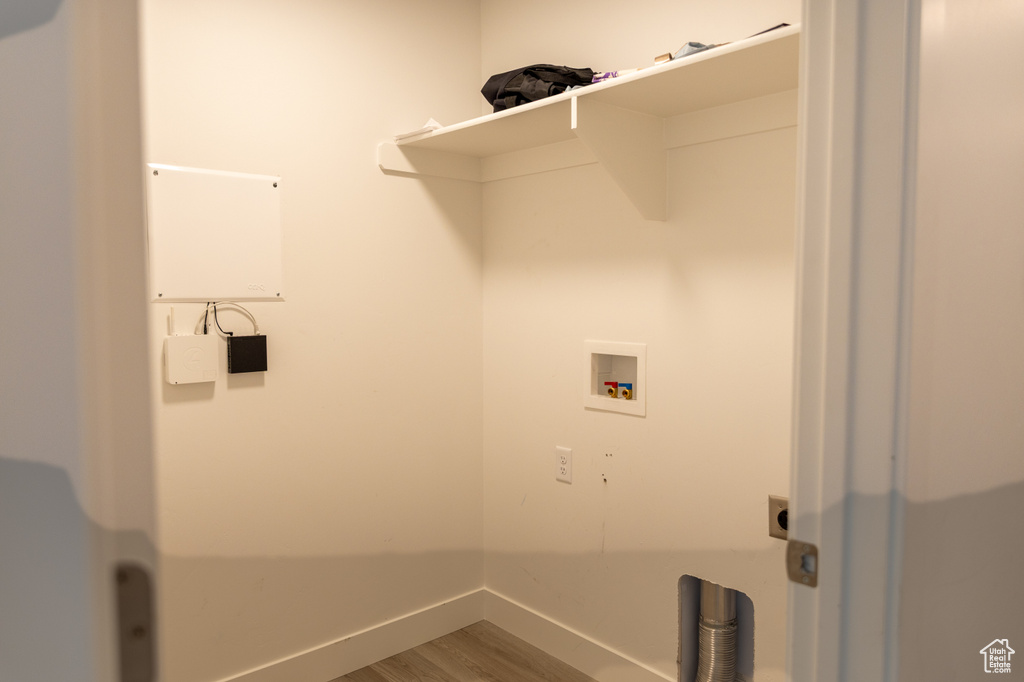 Clothes washing area featuring hookup for a washing machine, hookup for an electric dryer, wood finished floors, and baseboards