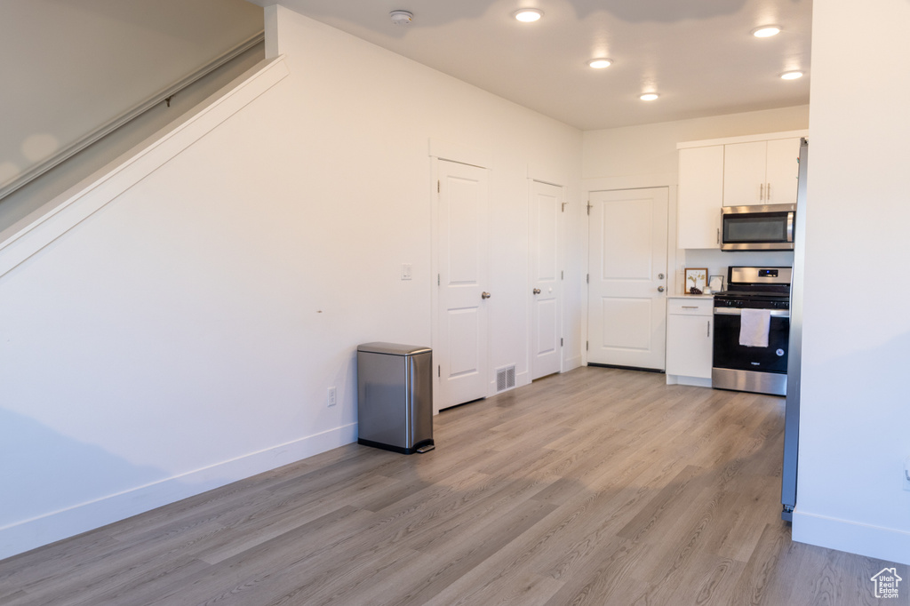 Kitchen featuring stainless steel appliances, white cabinets, light wood-style floors, baseboards, and recessed lighting