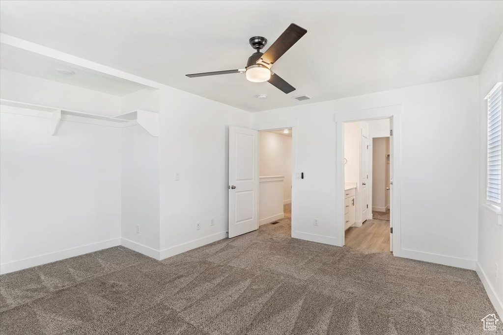 Unfurnished bedroom with light colored carpet, baseboards, ceiling fan, and connected bathroom