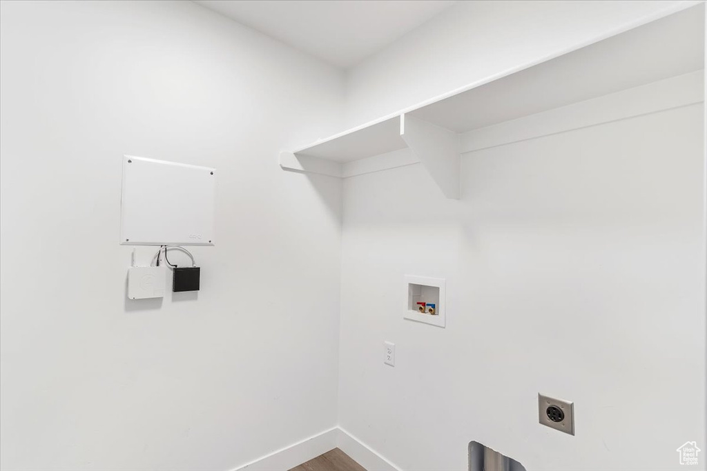 Laundry room with hookup for a washing machine, hookup for an electric dryer, baseboards, and wood finished floors