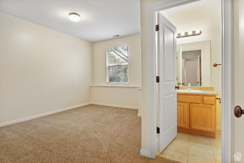 Hallway featuring a sink, light carpet, and baseboards