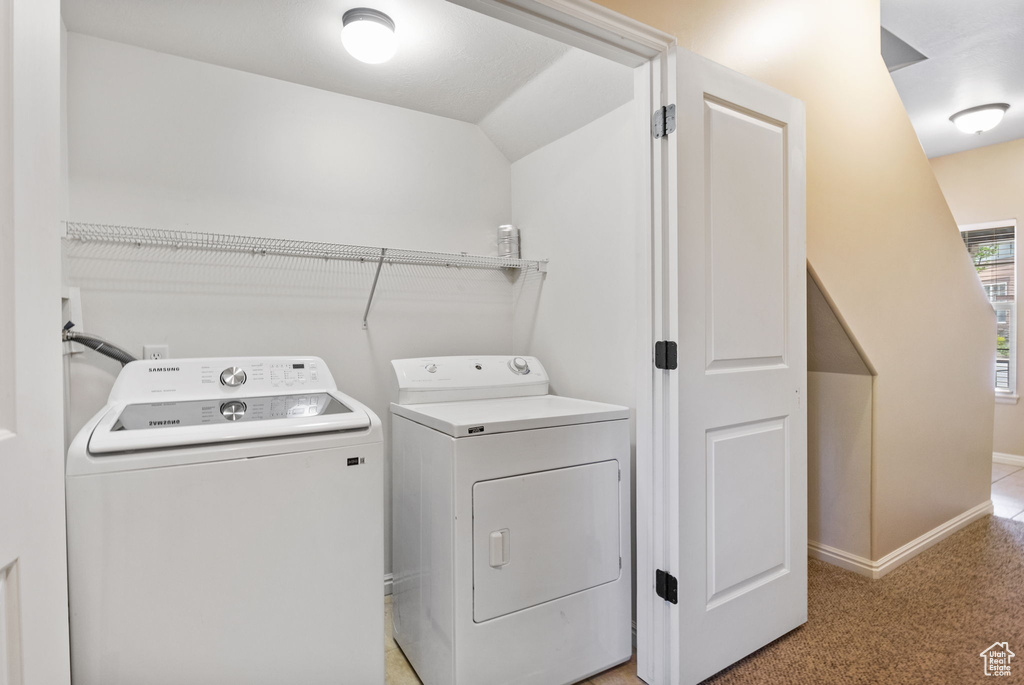 Washroom with washing machine and clothes dryer, baseboards, and light colored carpet