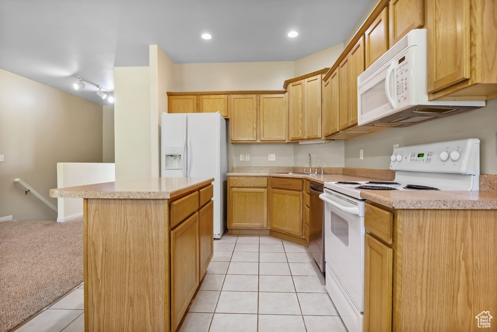 Kitchen featuring white appliances, a sink, a kitchen island, light countertops, and light tile patterned floors
