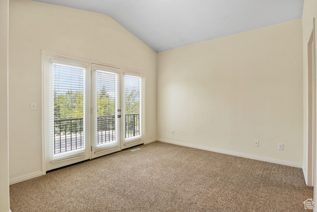 Carpeted empty room with vaulted ceiling and baseboards