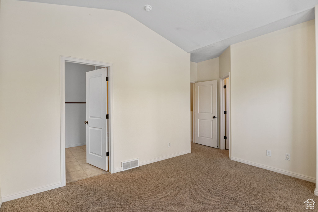 Spare room with carpet flooring, vaulted ceiling, baseboards, and a smoke detector