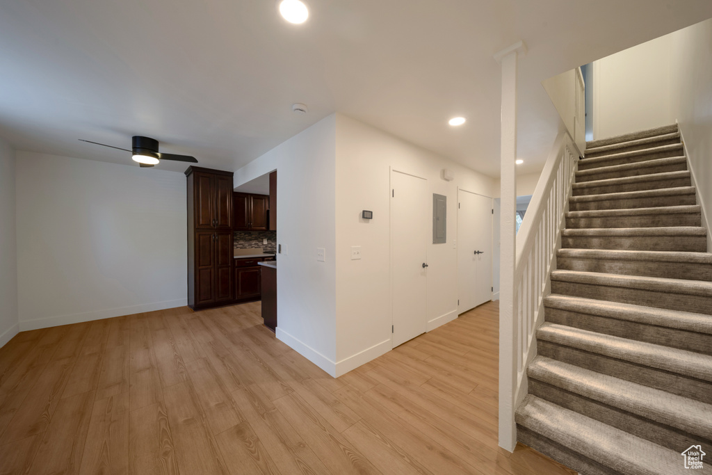Stairs with electric panel, wood finished floors, baseboards, and recessed lighting