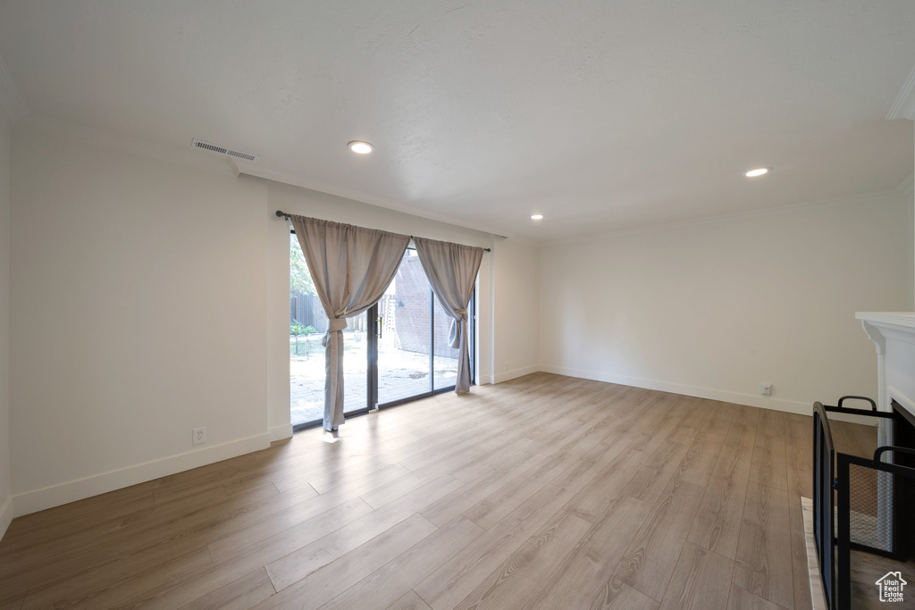 Unfurnished living room featuring light wood-type flooring, baseboards, ornamental molding, and recessed lighting