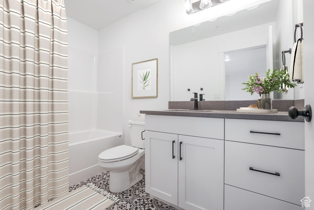 Bathroom featuring toilet, tile patterned floors, vanity, and shower / bath combo