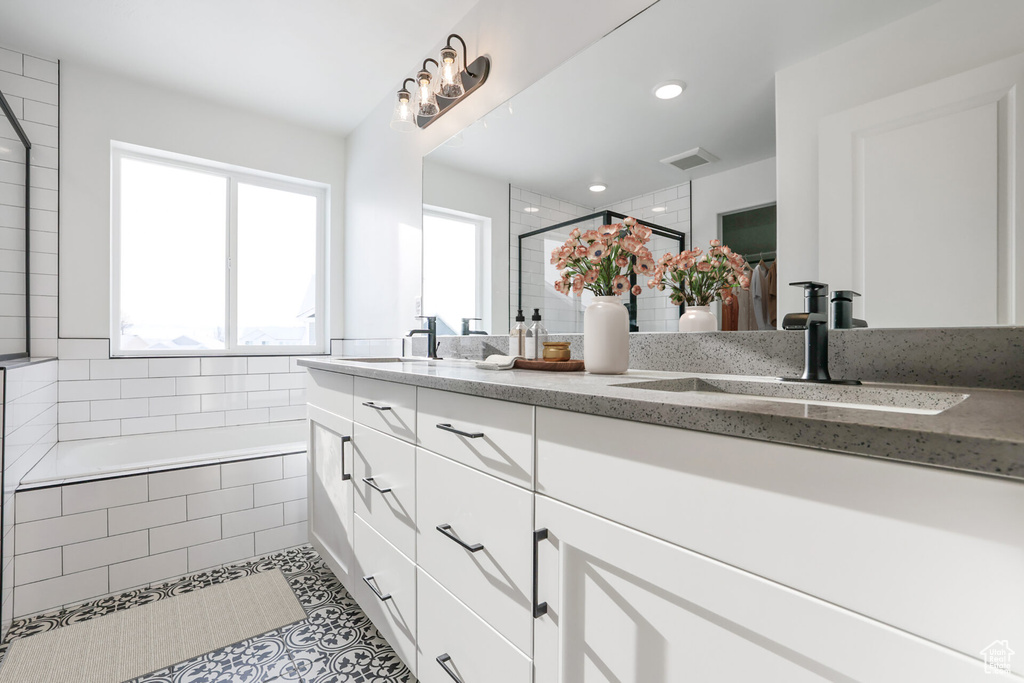 Bathroom featuring a stall shower, double vanity, tile patterned flooring, tiled bath, and recessed lighting
