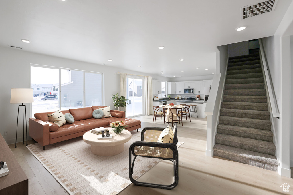 Living room with stairs, light wood-style flooring, and recessed lighting