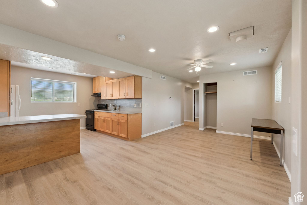 Kitchen featuring black range with electric cooktop, light wood-style floors, freestanding refrigerator, light countertops, and recessed lighting