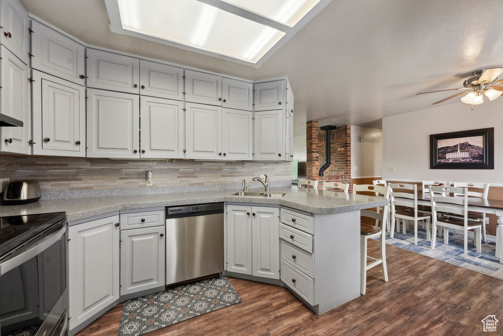Kitchen with stainless steel appliances, a sink, a peninsula, a breakfast bar area, and decorative backsplash