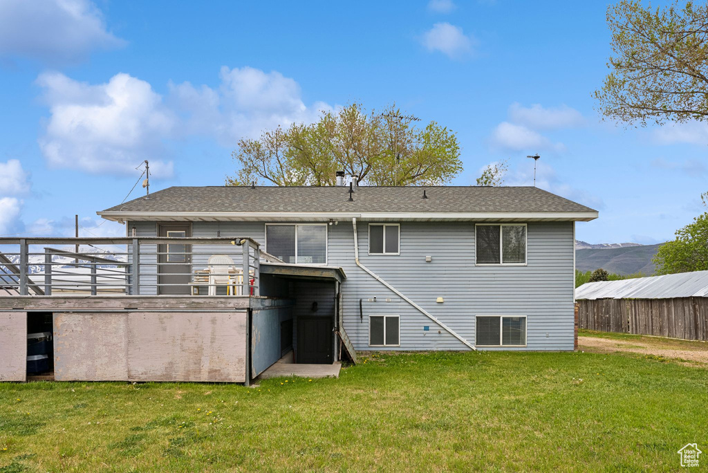 Rear view of property with a lawn and a shingled roof