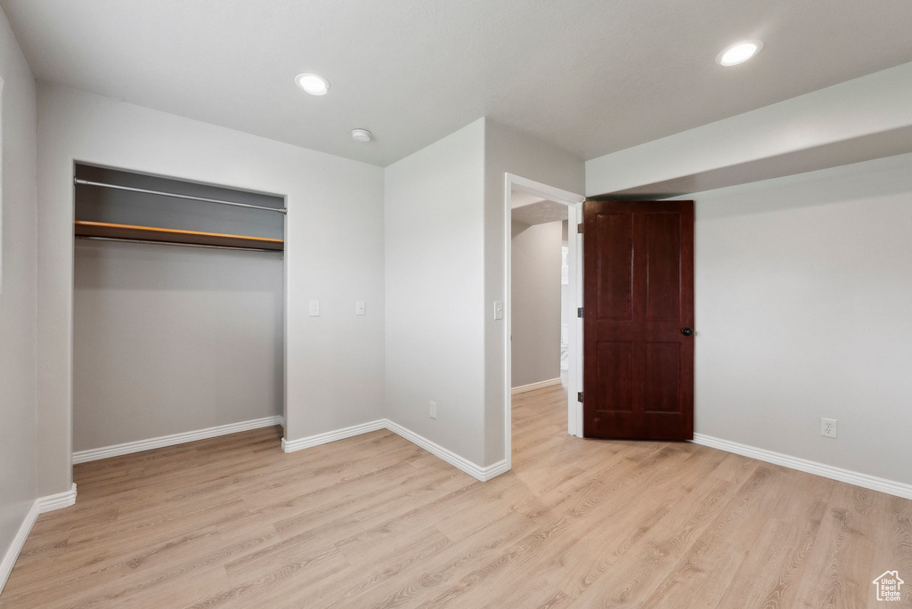 Unfurnished bedroom featuring light wood-style floors, baseboards, recessed lighting, and a closet