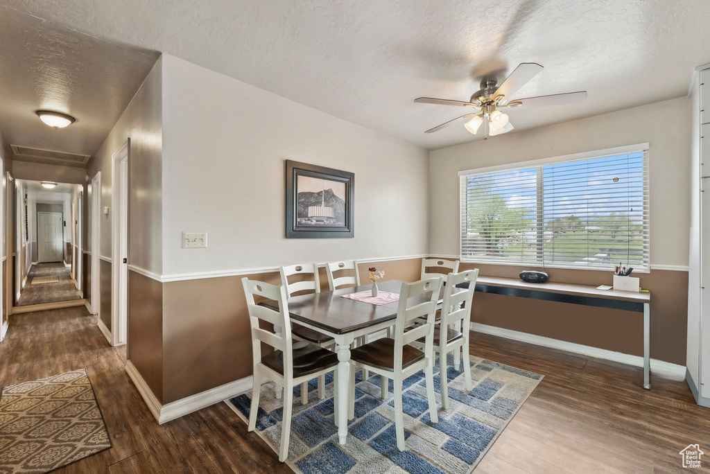 Dining area featuring wood finished floors, baseboards, ceiling fan, and a textured ceiling