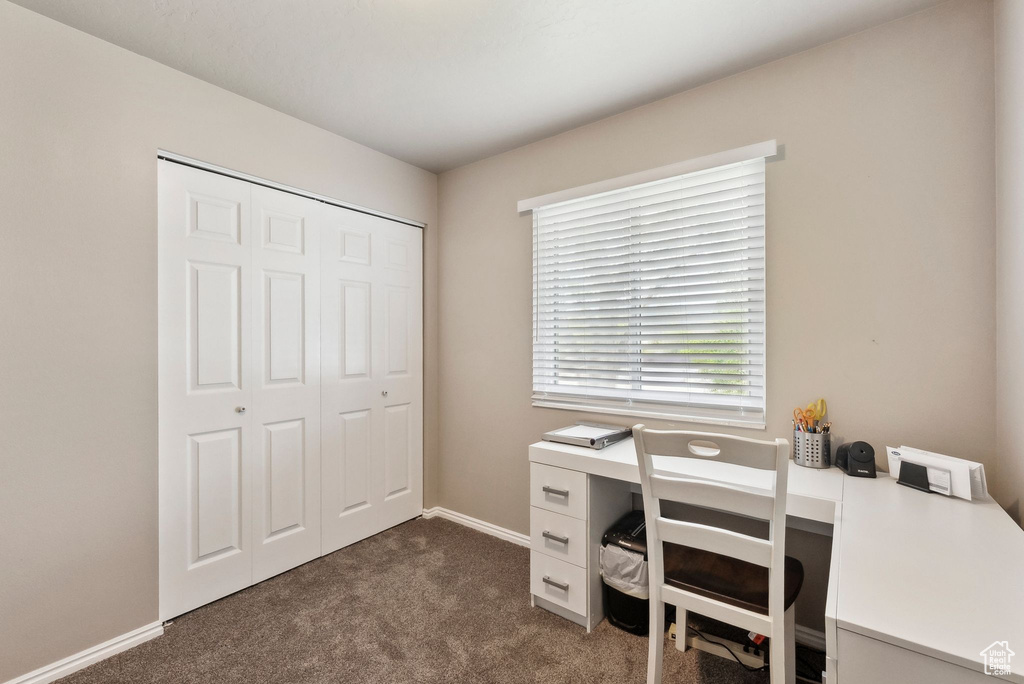 Office area featuring dark carpet and baseboards
