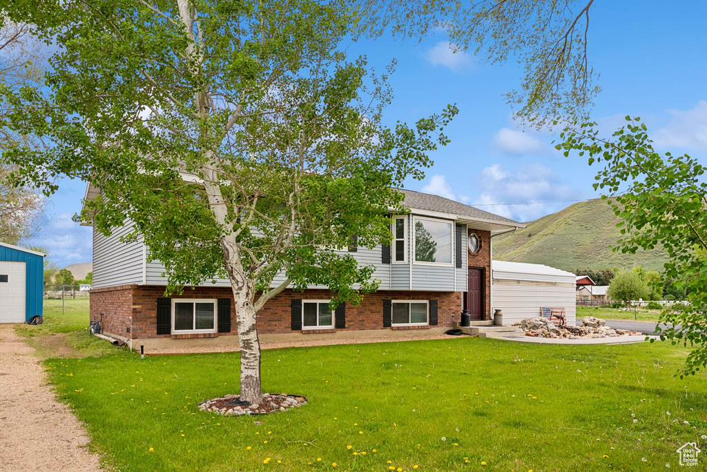 View of front facade featuring brick siding, a front lawn, a mountain view, and an outbuilding