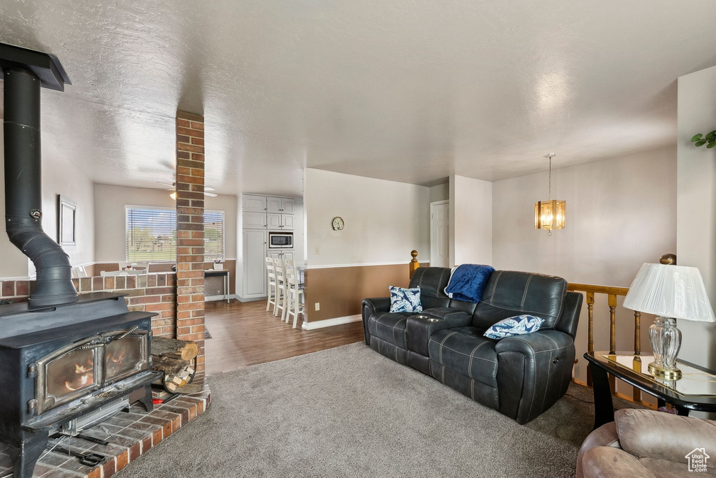 Carpeted living area featuring a wood stove, a chandelier, baseboards, and wood finished floors