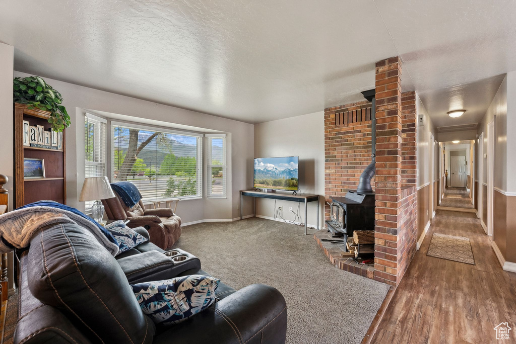 Living room featuring a wood stove, baseboards, and wood finished floors