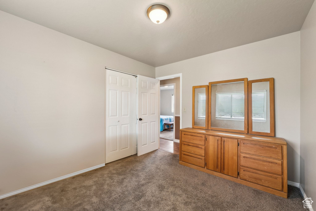 Bedroom featuring dark colored carpet, baseboards, and a closet