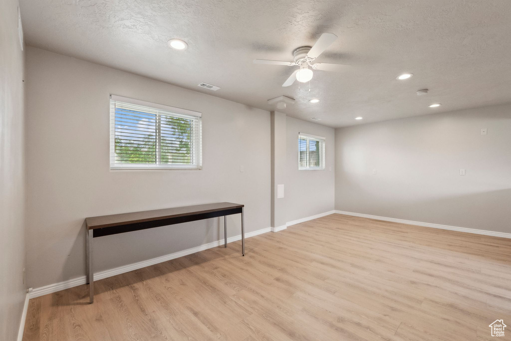 Unfurnished room featuring healthy amount of natural light, light wood-style flooring, a textured ceiling, recessed lighting, and baseboards