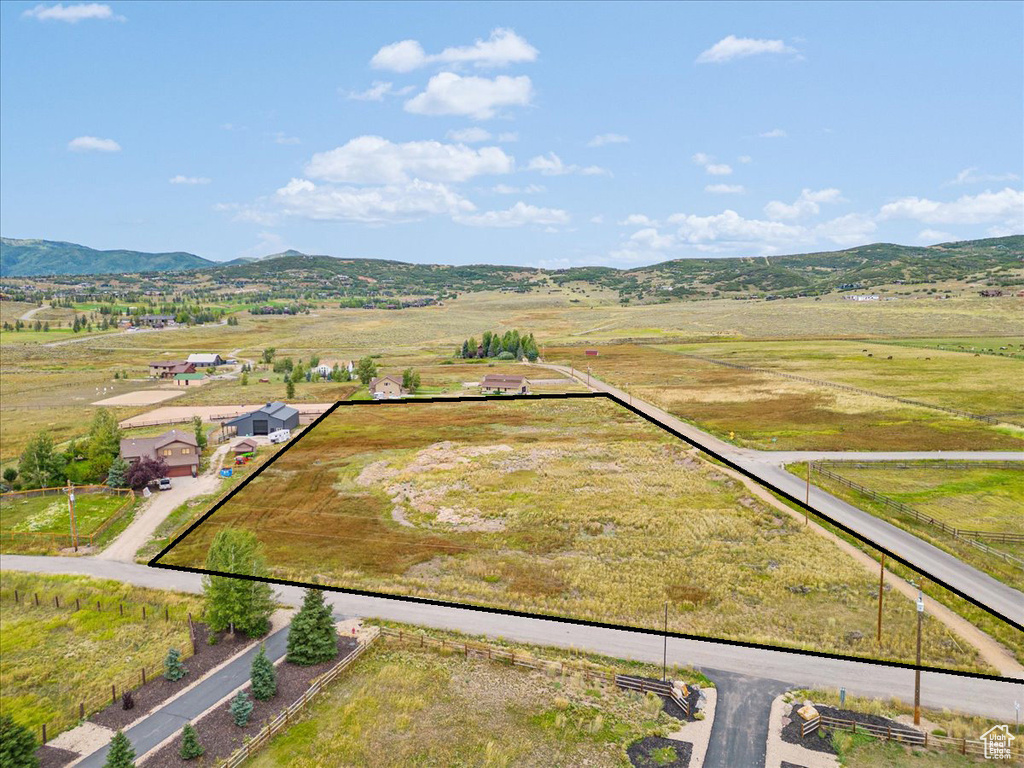 Aerial view of sparsely populated area with property parcel outlined and a mountainous background