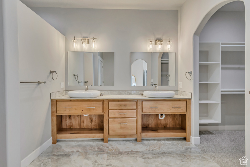 Bathroom with double vanity, a spacious closet, and baseboards