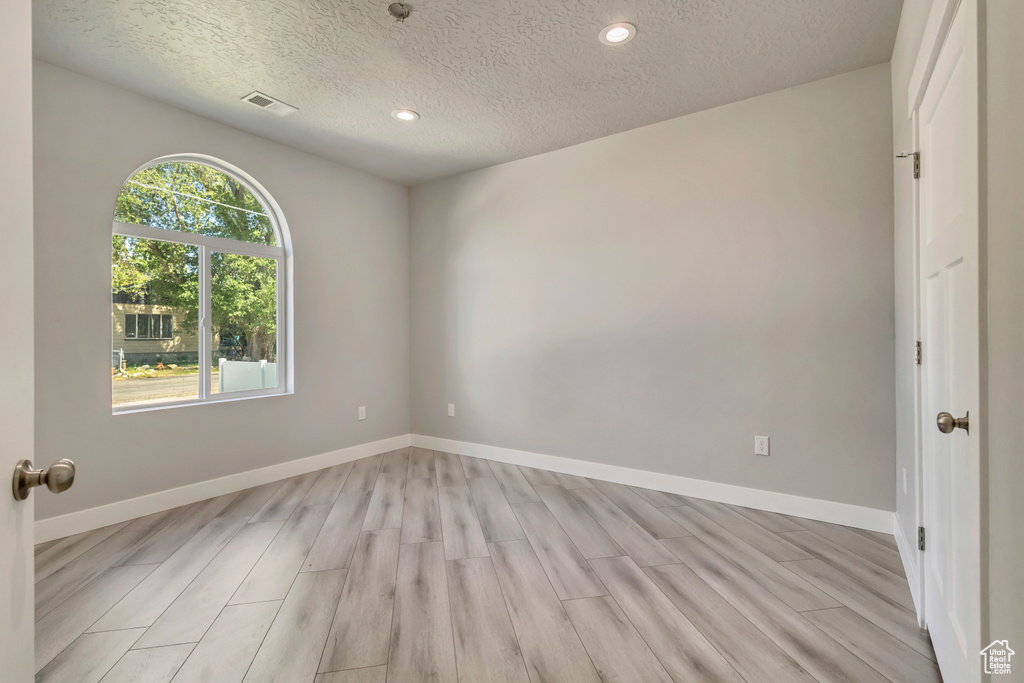 Spare room featuring a textured ceiling, light wood finished floors, recessed lighting, and baseboards
