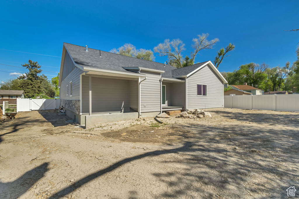 Back of property featuring fence, a gate, and roof with shingles
