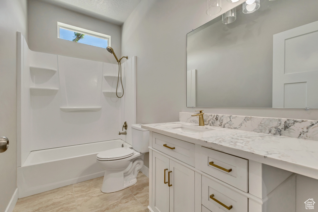 Bathroom featuring toilet, vanity, shower / bath combination, and baseboards