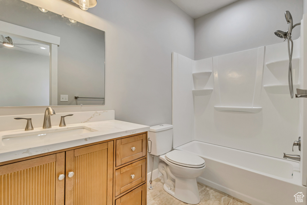 Bathroom featuring toilet, vanity, ceiling fan, and shower / tub combination