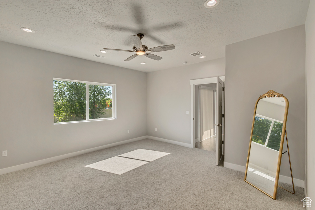 Carpeted spare room with plenty of natural light, a textured ceiling, recessed lighting, ceiling fan, and baseboards