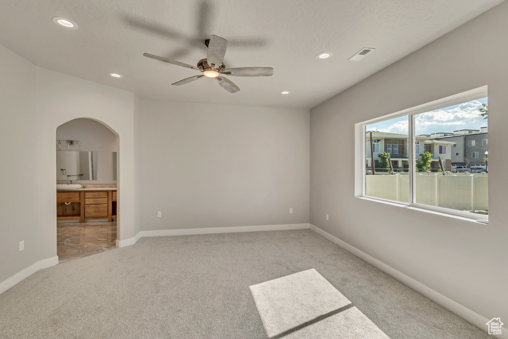 Empty room with light colored carpet, arched walkways, recessed lighting, a ceiling fan, and baseboards