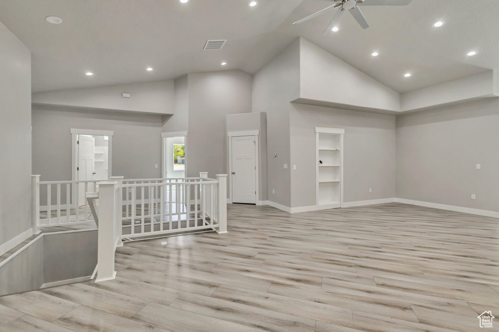 Empty room with a ceiling fan, light wood finished floors, baseboards, recessed lighting, and high vaulted ceiling