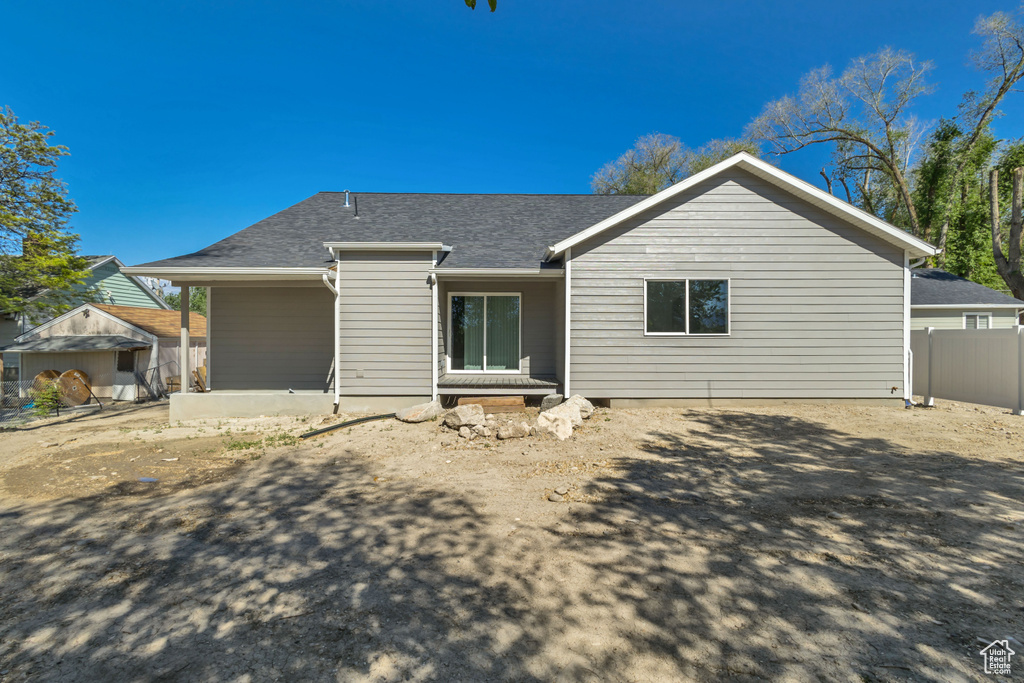 Back of house featuring fence and a shingled roof
