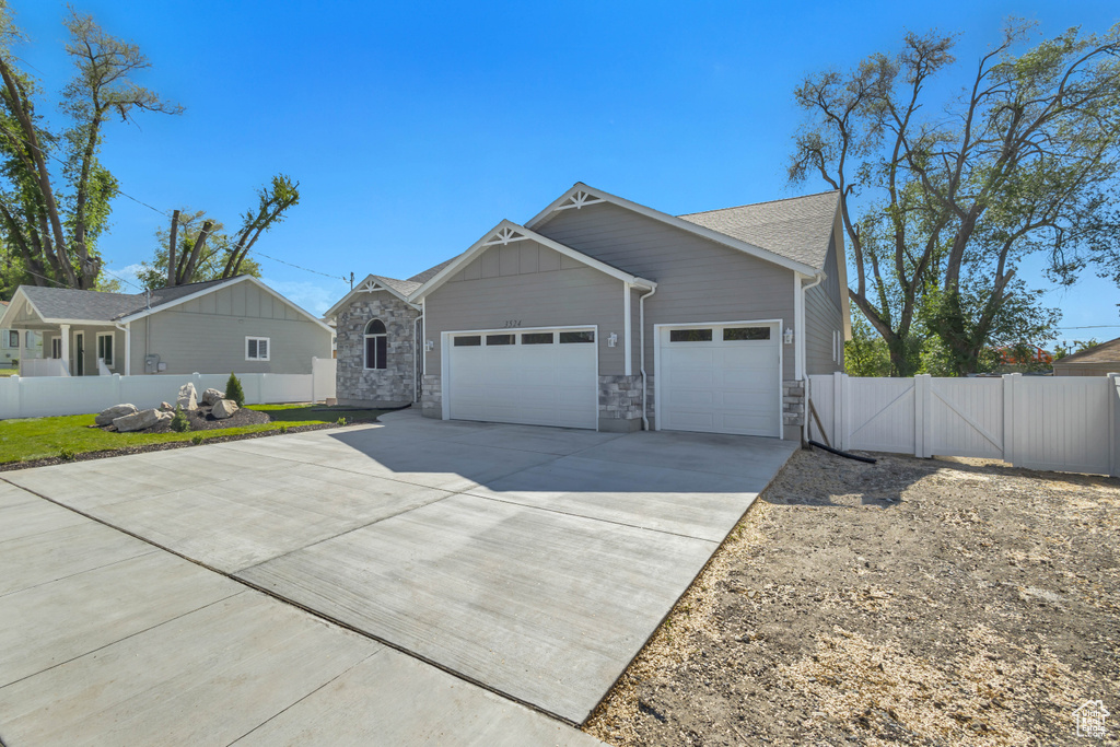 View of front of home with a garage, fence, concrete driveway, a gate, and stone siding