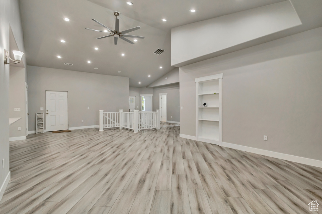 Unfurnished living room with high vaulted ceiling, recessed lighting, ceiling fan, baseboards, and light wood-style floors