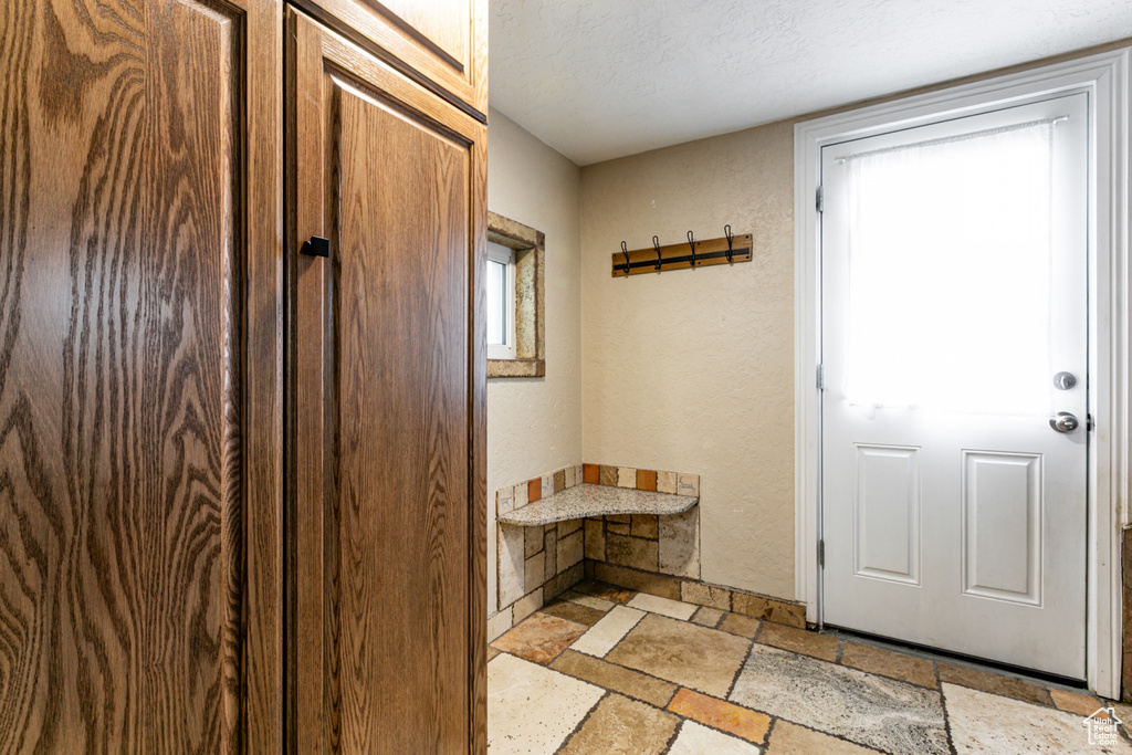 Mudroom featuring stone tile flooring and a textured wall